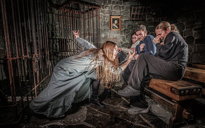 Visitors react to a performer in a spooky scene at the London Dungeon.