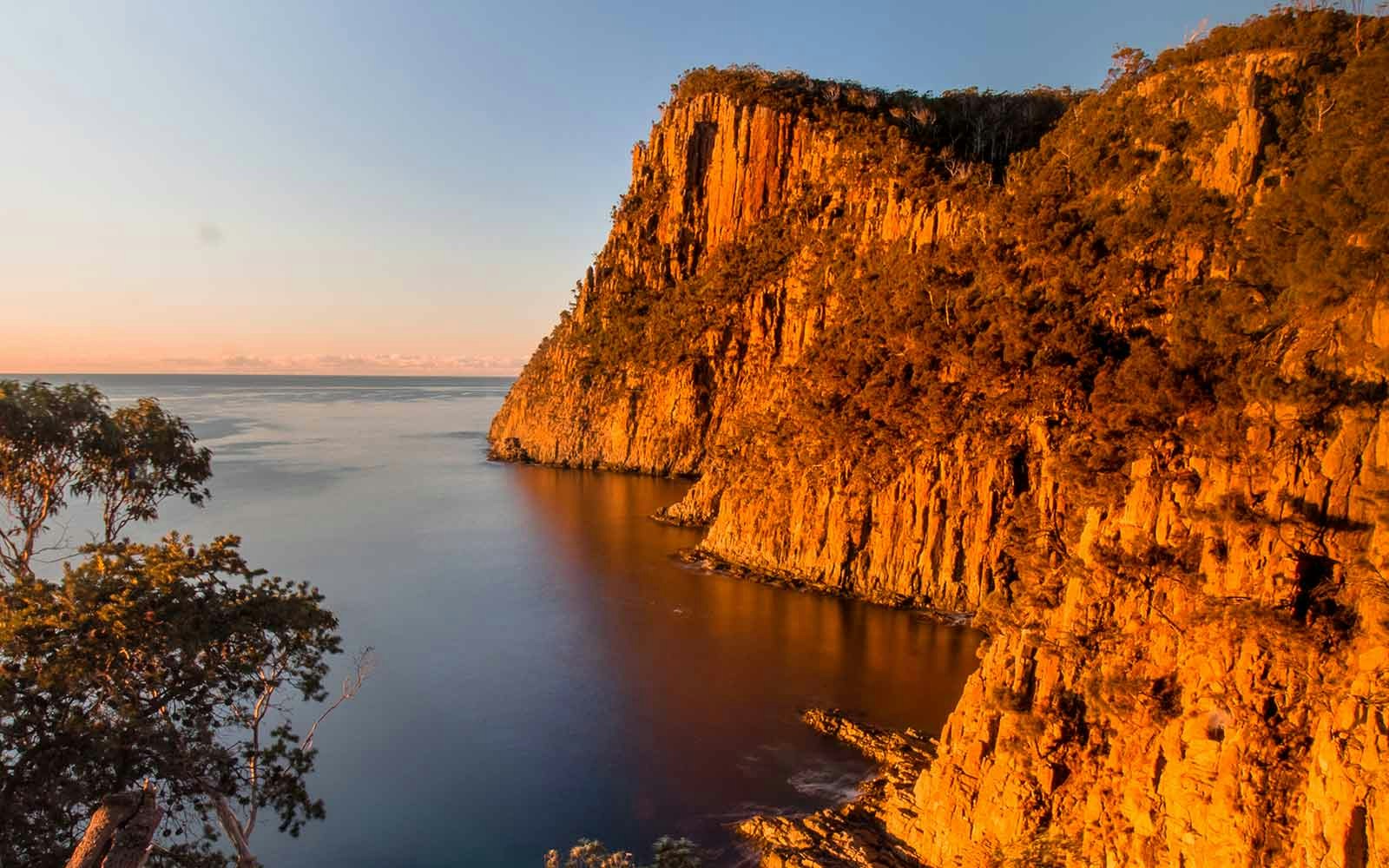 Hikers on a trail overlooking the ocean at sunrise, Fluted Cape, Bruny Island, Tasmania.