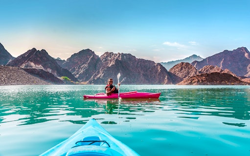 Kayaking on Hatta Dam with mountain views during Heritage Village Tour.
