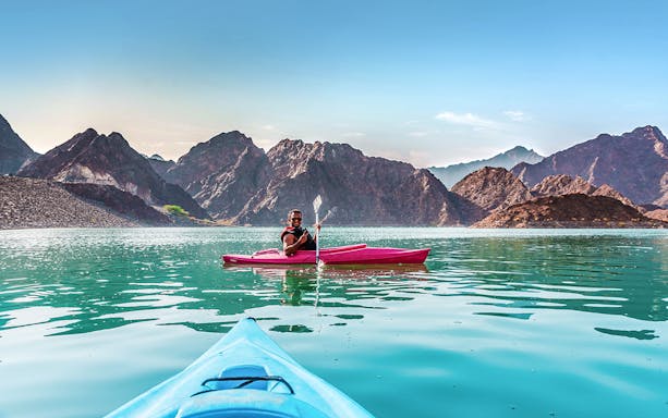 Kayaking on Hatta Dam with mountain views during Heritage Village Tour.