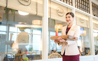 Server holding a drink at Coral International Lounge, Phuket International Airport.