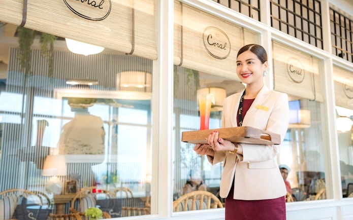 Server holding a drink at Coral International Lounge, Phuket International Airport.