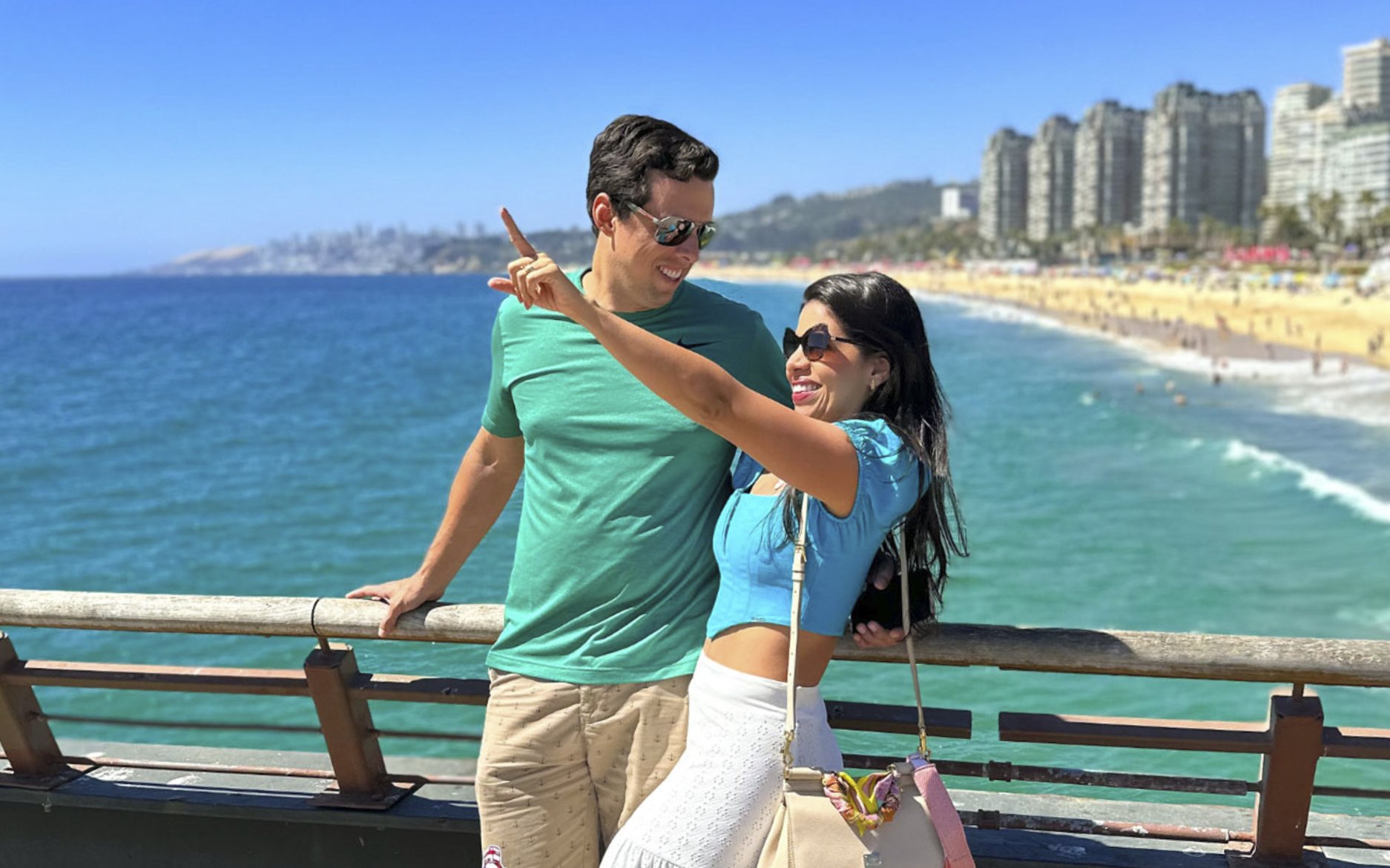 Tourists enjoying the view from the bridge at Wuff Castle with ocean and cityscape in the background.