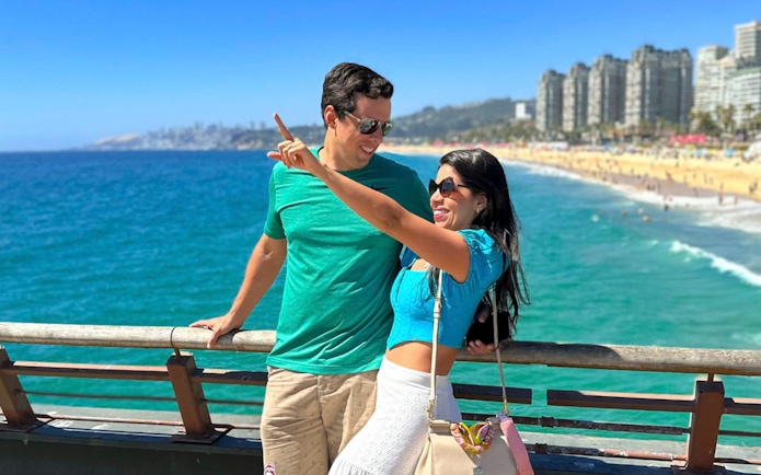 Tourists enjoying the view from the bridge at Wuff Castle with ocean and cityscape in the background.
