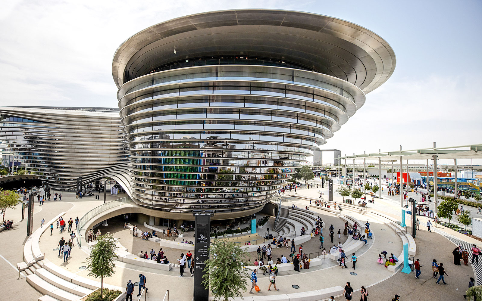 Aerial view of Expo City Dubai entrance with modern architecture and visitors.