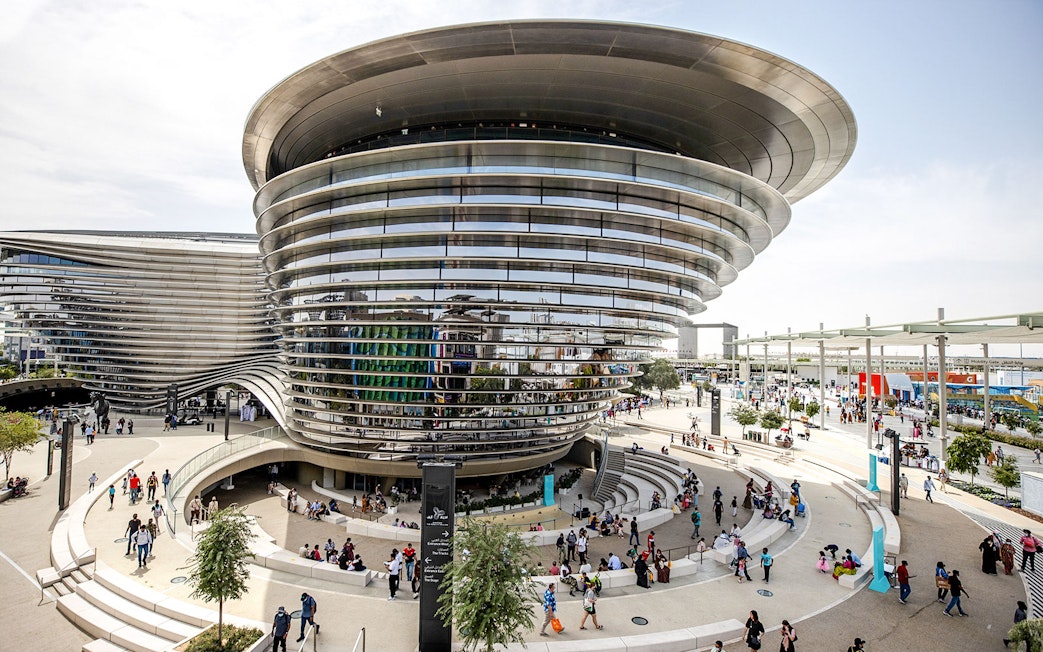 Aerial view of Expo City Dubai entrance with modern architecture and visitors.