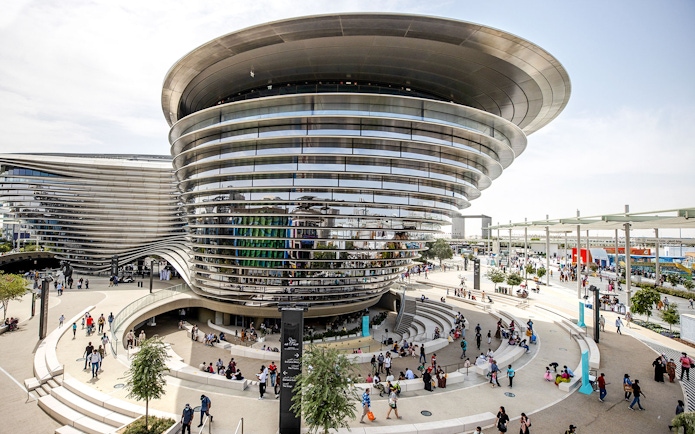 Aerial view of Expo City Dubai entrance with modern architecture and visitors.