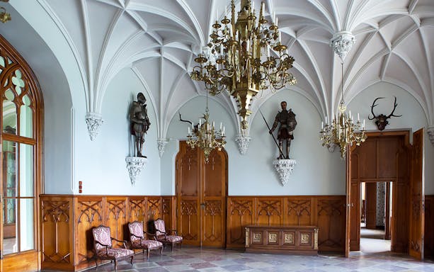 Interior of Malbork Castle with ornate chandeliers and knight statues, Poland.