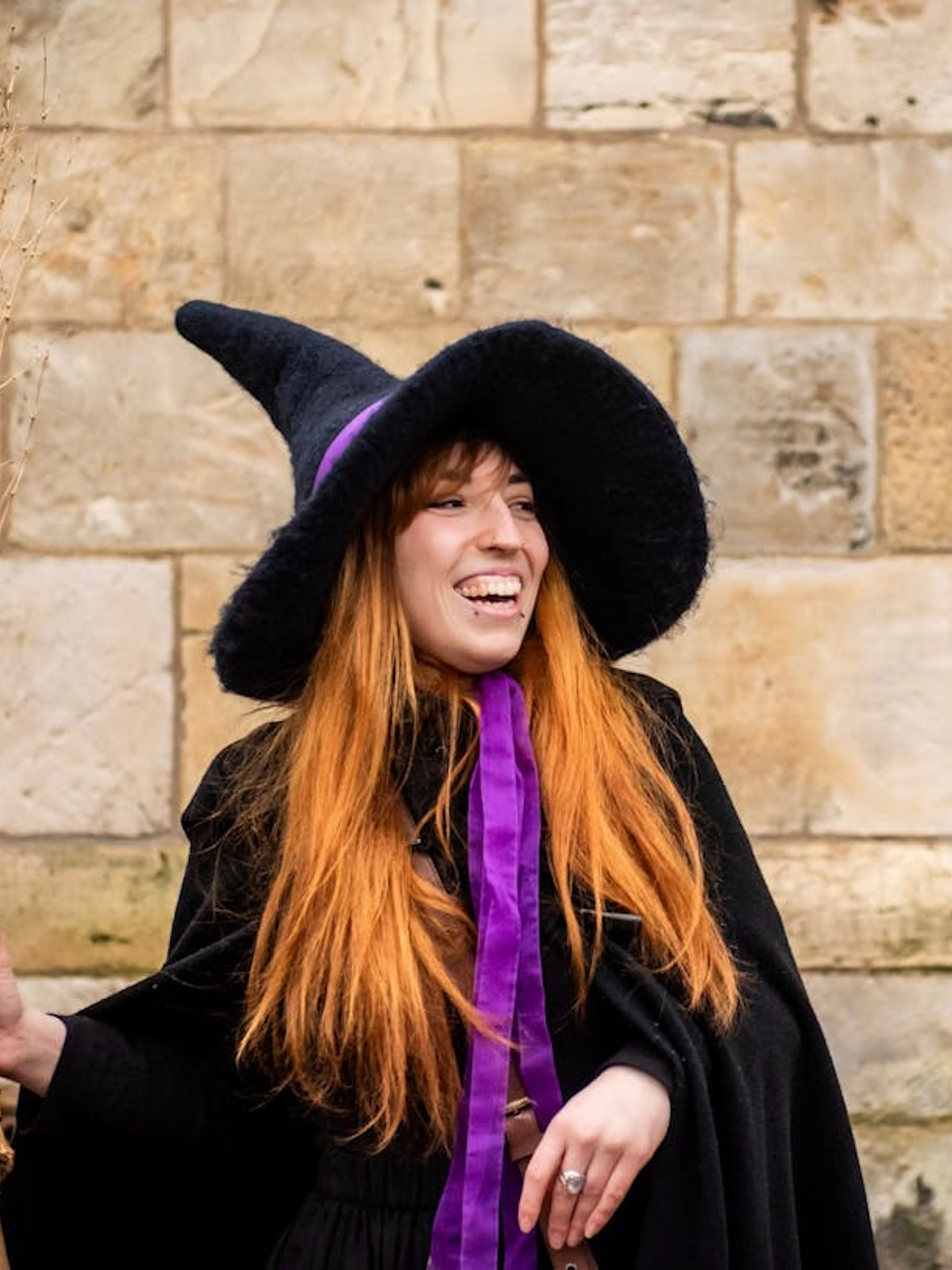 Tour guide in witch costume holding broom on York Witches & History Old Town Walking Tour.