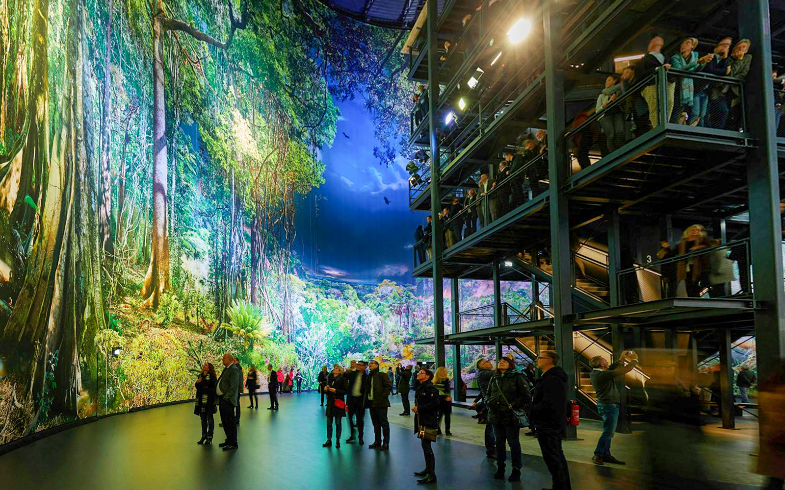 Visitors exploring panoramic rainforest exhibit at Panometer Dresden.