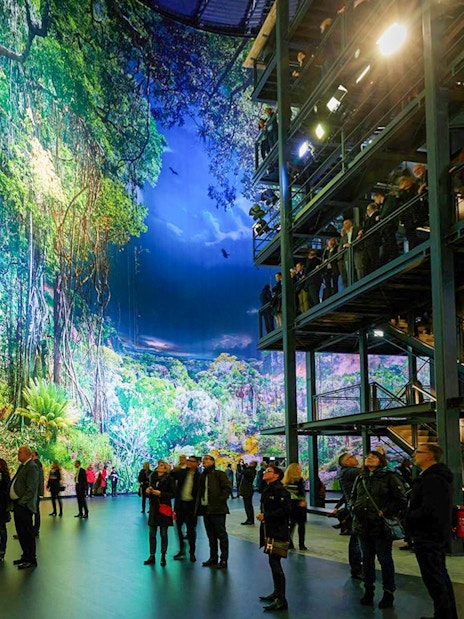 Visitors exploring panoramic rainforest exhibit at Panometer Dresden.