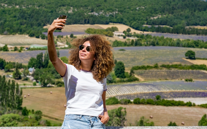Person taking a selfie with lavender fields in Sault, France in the background.