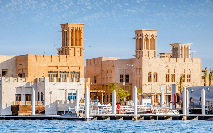 Traditional buildings along Dubai Creek with wind towers and waterfront view.