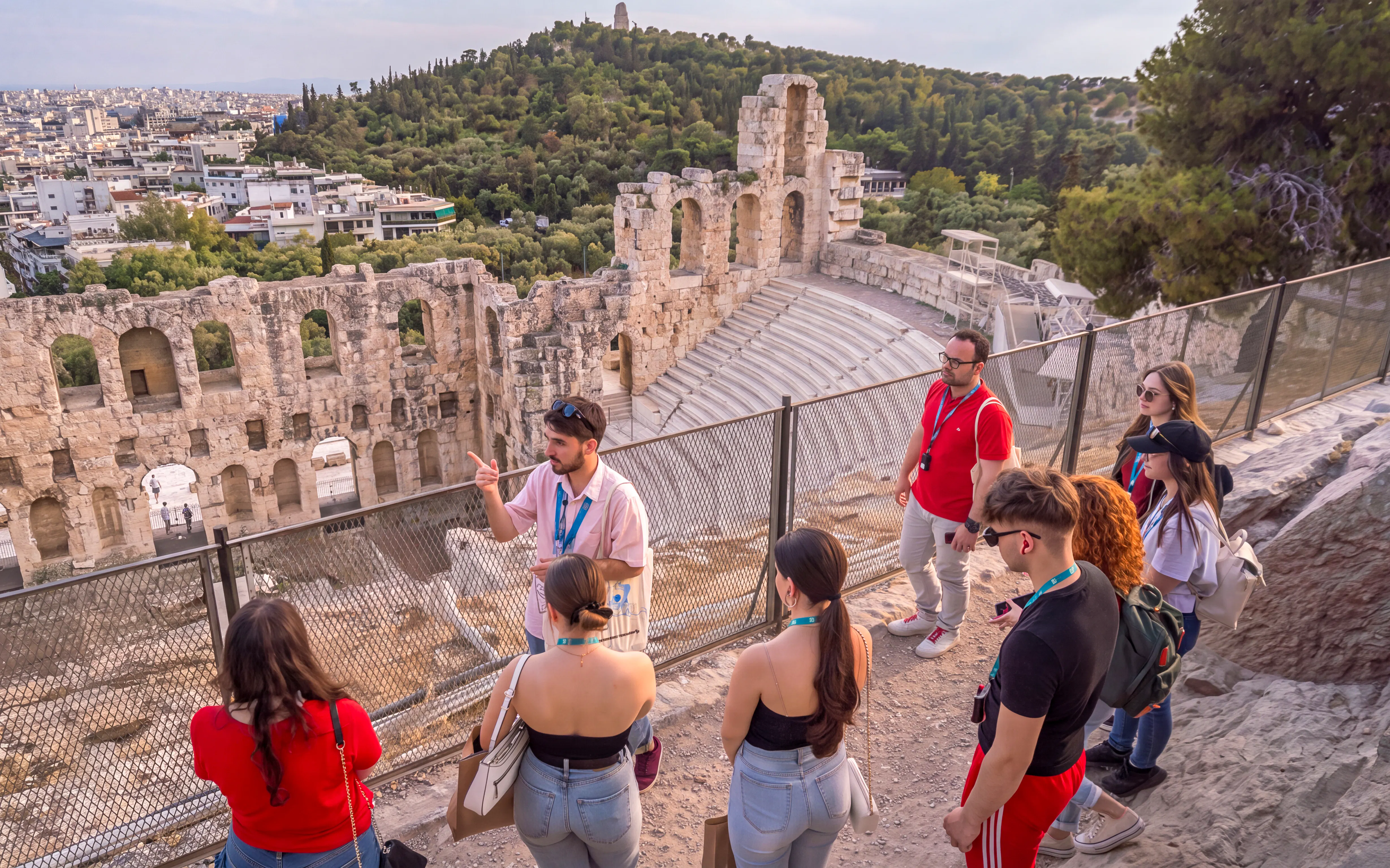 Tour group with guide at the Acropolis overlooking the Odeon of Herodes Atticus in Athens.