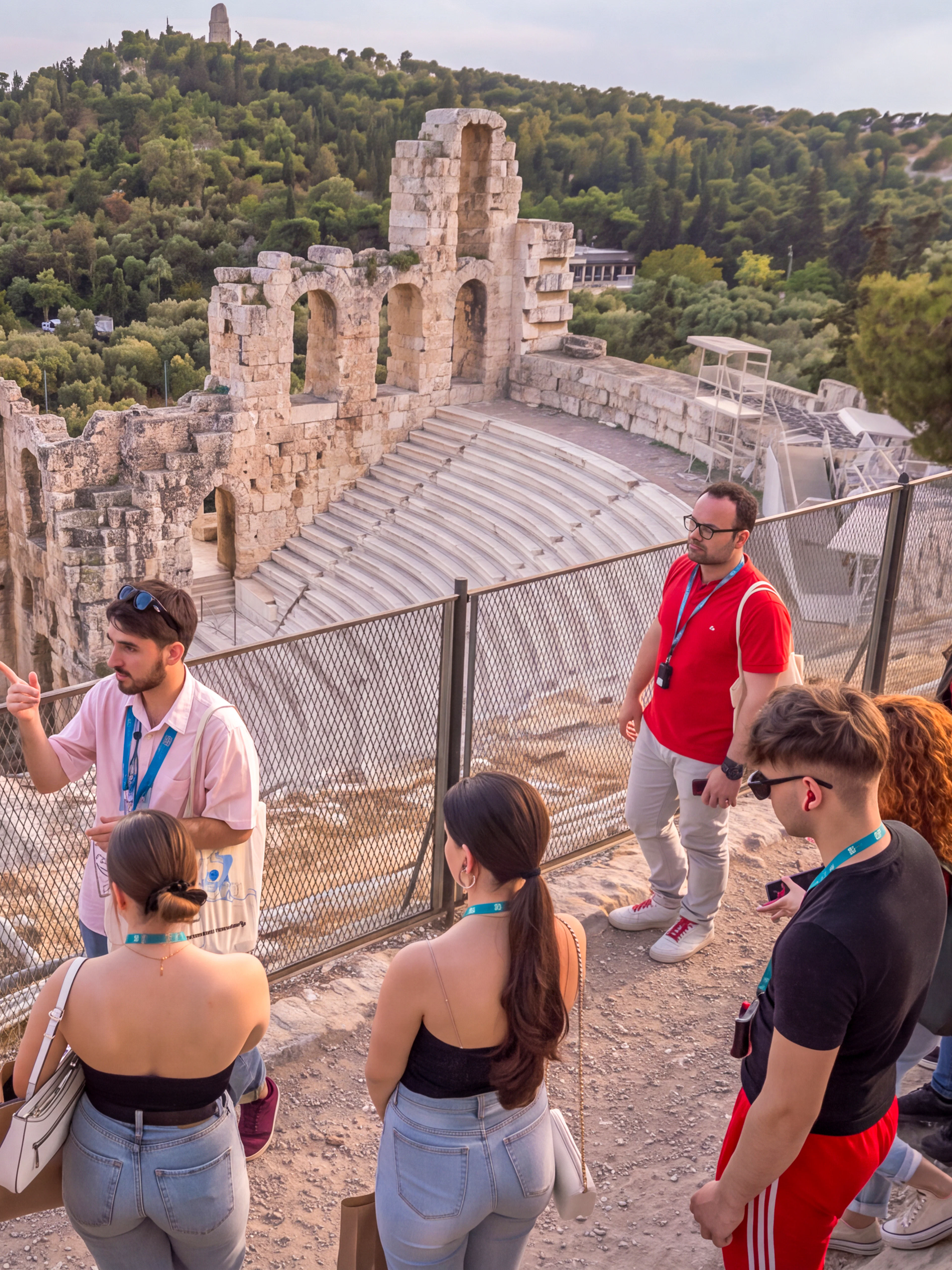 Tour group with guide at the Acropolis overlooking the Odeon of Herodes Atticus in Athens.