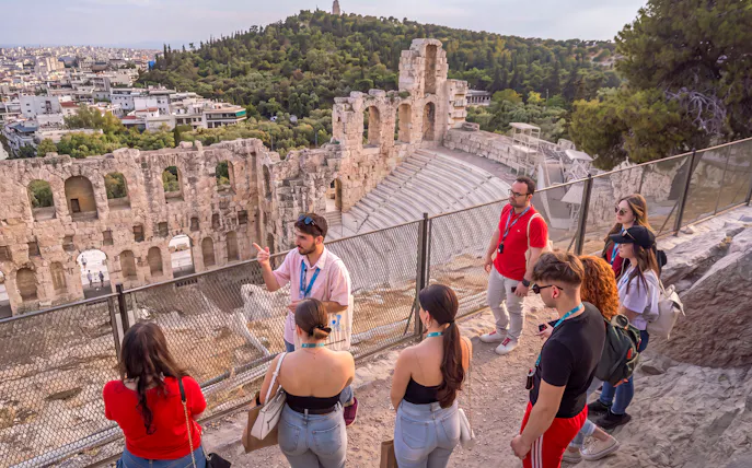 Tour group with guide at the Acropolis overlooking the Odeon of Herodes Atticus in Athens.