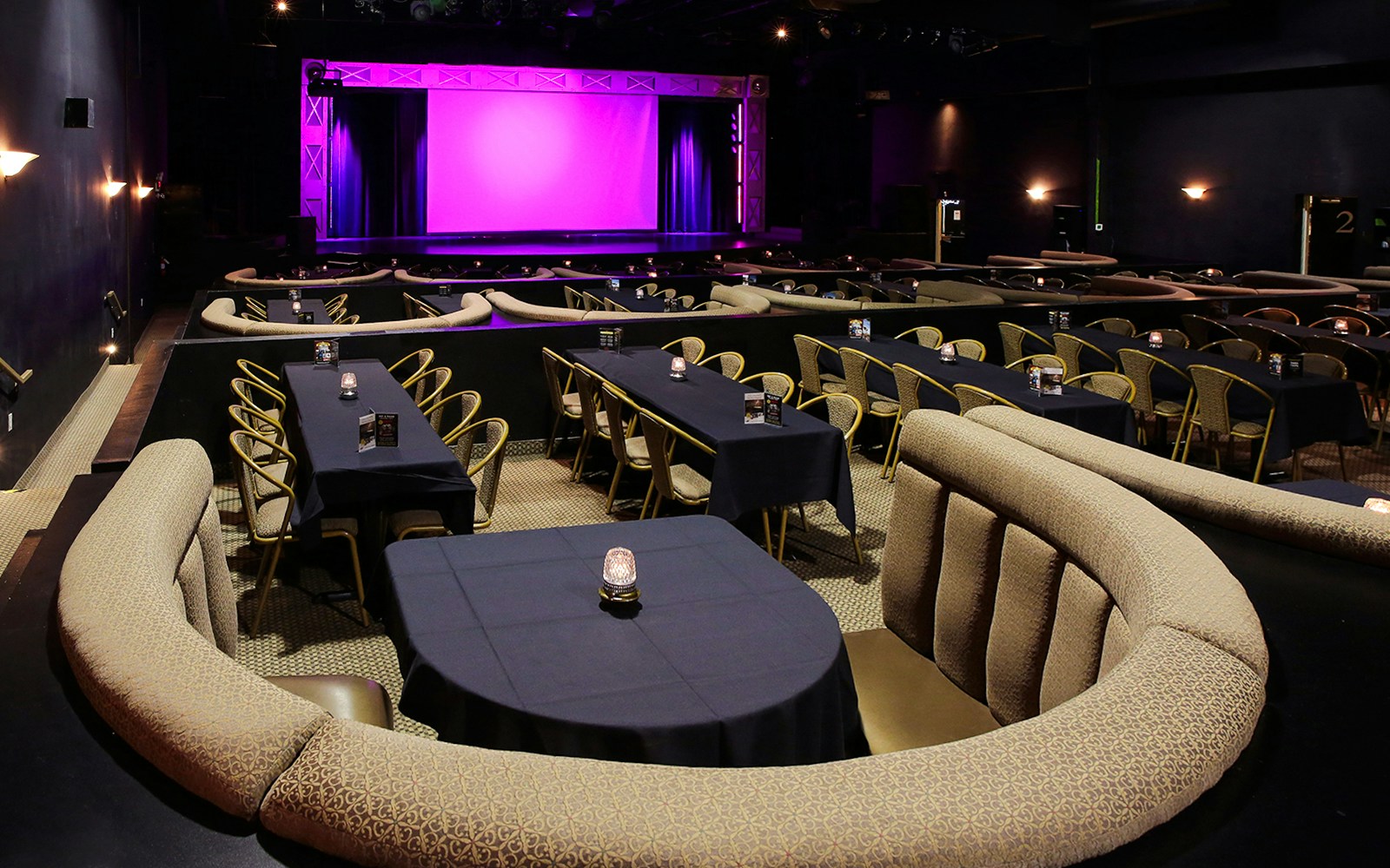 Cozy theater seating with tables facing a stage set for the Evolution Magic Show.