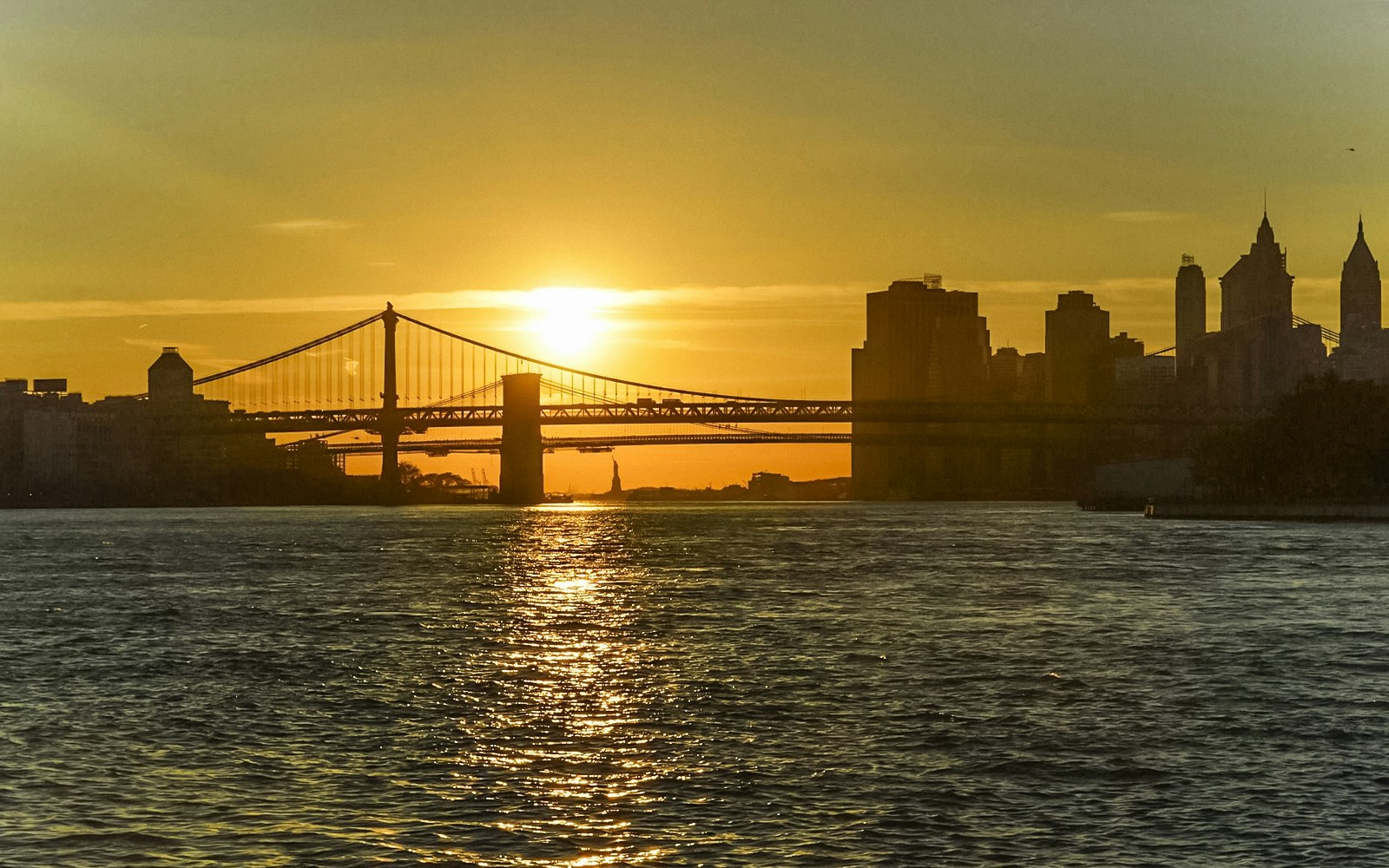 Statue of Liberty and Ellis Island at sunset during a scenic cruise in New York Harbor.