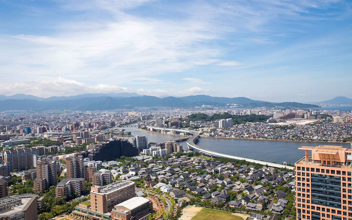 Aerial view of Fukuoka cityscape with river and mountains, seen from Fukuoka Tower.