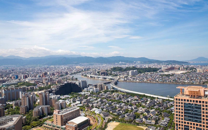 Aerial view of Fukuoka cityscape with river and mountains, seen from Fukuoka Tower.