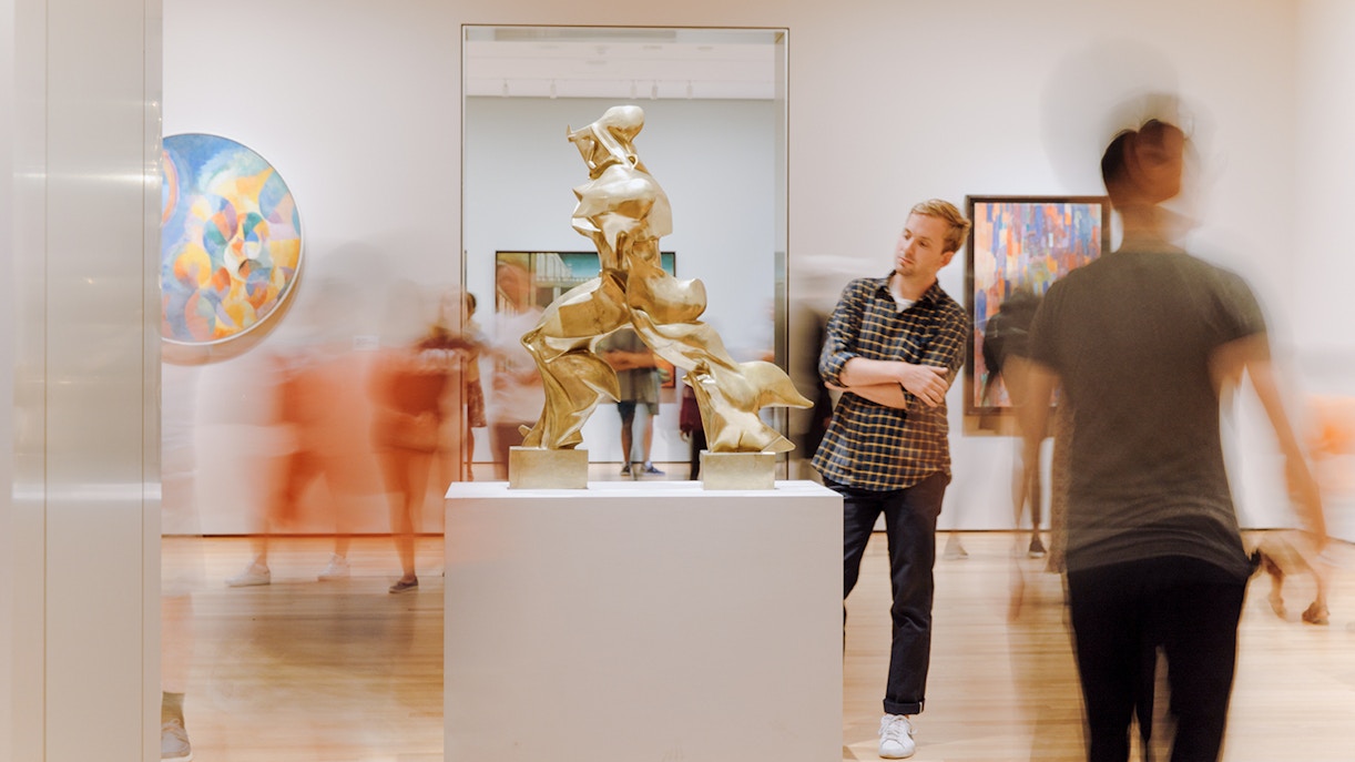 Man observing Boccioni sculpture at MoMA, New York City.