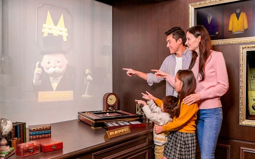 Family interacting with Mr. Monopoly hologram at Monopoly Dreams Melbourne.