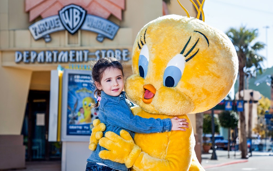 Child hugging Tweety character at Parque Warner Madrid.