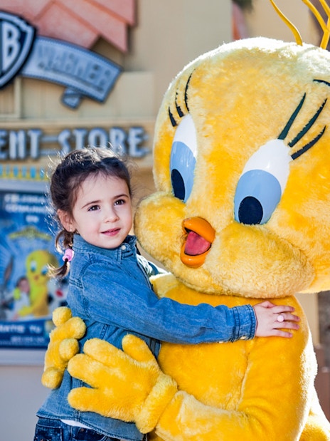 Child hugging Tweety character at Parque Warner Madrid.