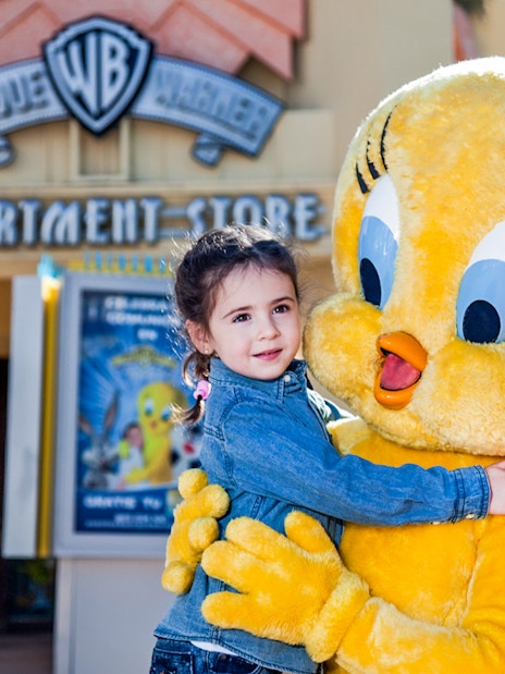 Child hugging Tweety character at Parque Warner Madrid.