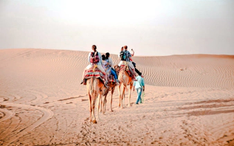 Camel trekking tour in Abu Dhabi desert with riders on camels.