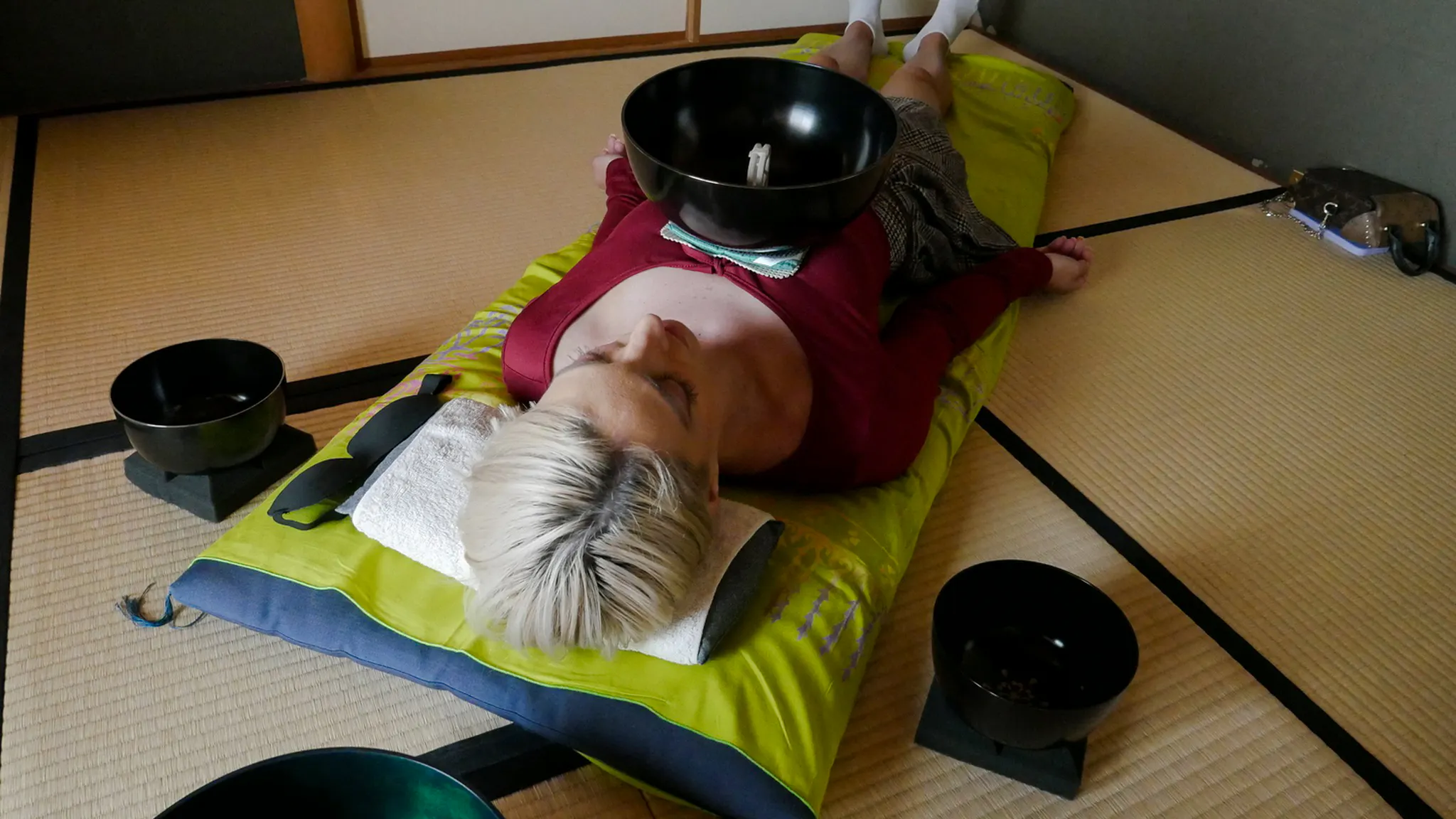 Person experiencing a Japanese sound bath with bowls on a tatami mat in Kyoto.
