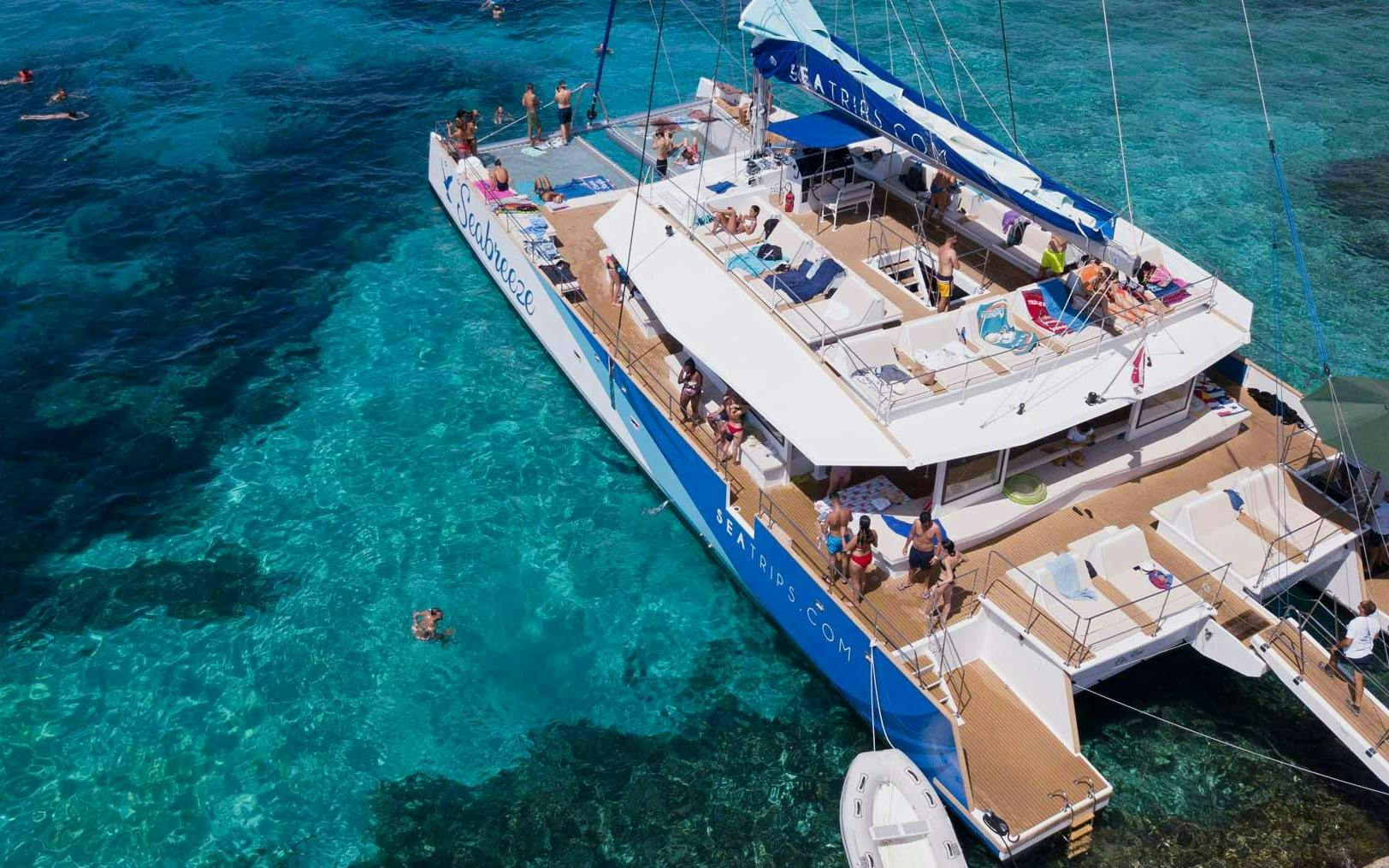 Catamaran with tourists at Blue Lagoon, people swimming in clear turquoise water.