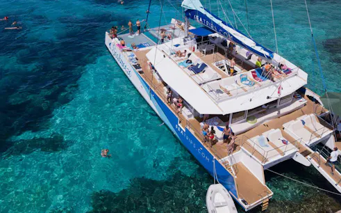 Catamaran with tourists at Blue Lagoon, people swimming in clear turquoise water.