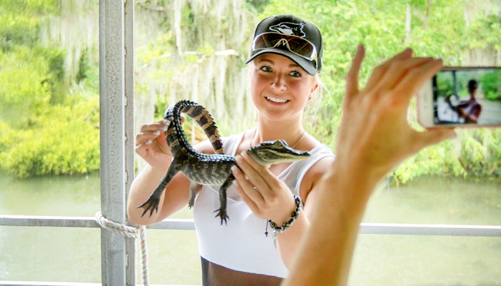 Person holding a baby alligator during a swamp tour near Oak Alley Plantation.