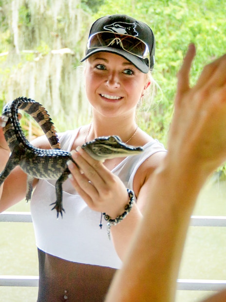 Person holding a baby alligator during a swamp tour near Oak Alley Plantation.