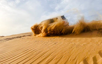 SUV driving through sand dunes during Abu Dhabi desert safari.