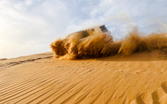 SUV driving through sand dunes during Abu Dhabi desert safari.