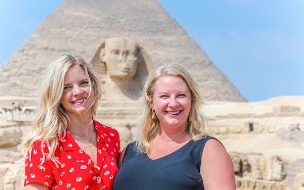 Tourists smiling in front of the Sphinx and Pyramid in Giza, Egypt.