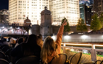 Chicago Haunted River "Creepy Cruise" passengers view illuminated buildings at night.
