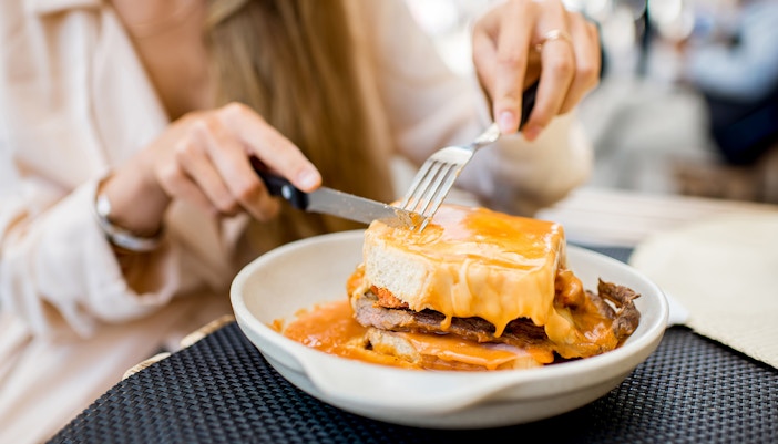 Francesinha sandwich with melted cheese and sauce in Porto restaurant.