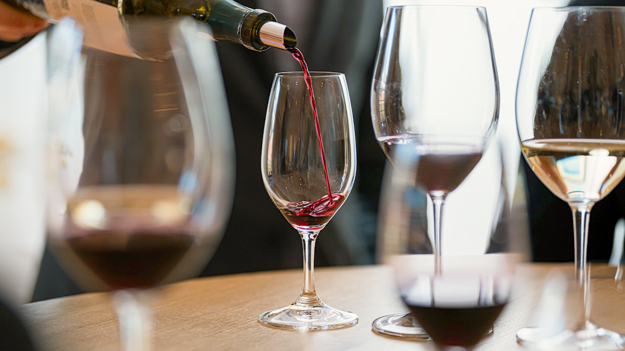 Pouring red wine into a glass at a wine tasting workshop.