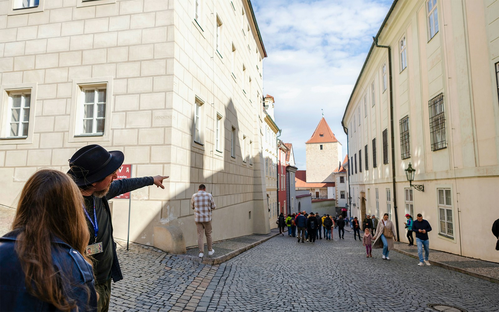 Guide pointing along cobblestone street on Golden Lane tour, Prague.
