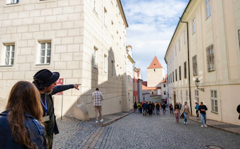 Guide pointing along cobblestone street on Golden Lane tour, Prague.