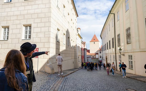 Guide pointing along cobblestone street on Golden Lane tour, Prague.