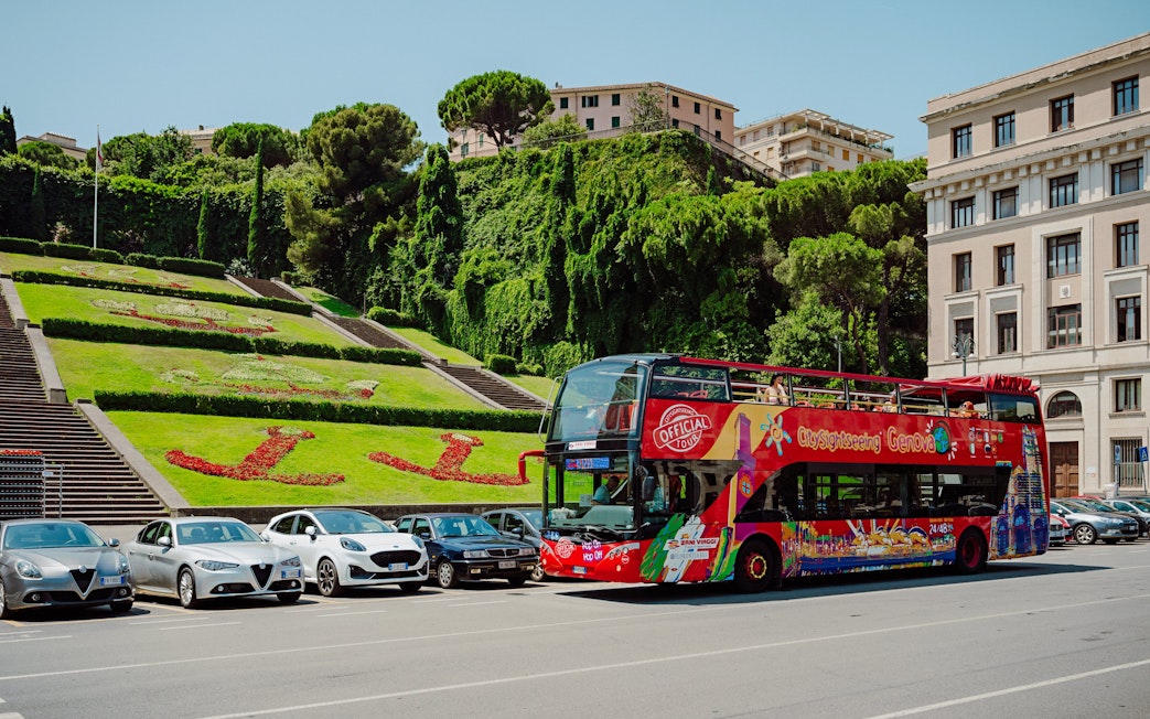 City Sightseeing bus parked near floral display in Genova, Italy.