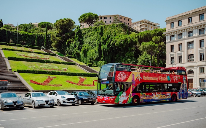 City Sightseeing bus parked near floral display in Genova, Italy.