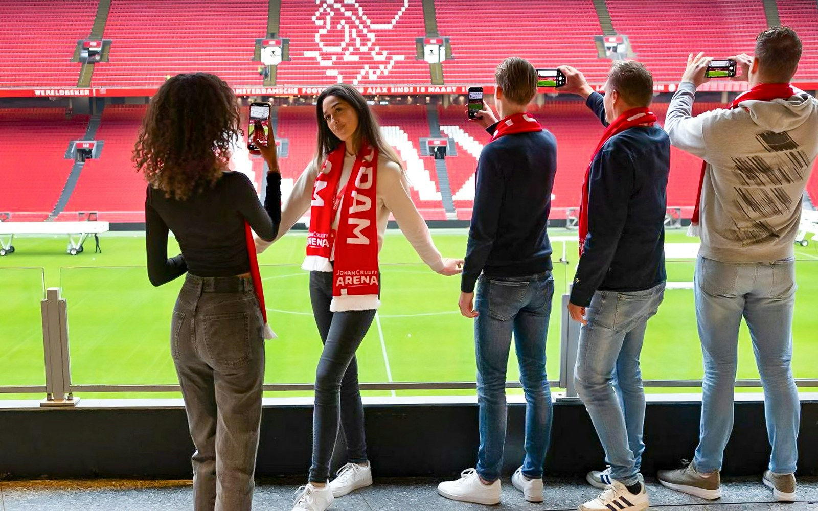 Een groep bezoekers neemt foto's van het veld vanaf de zijlijn