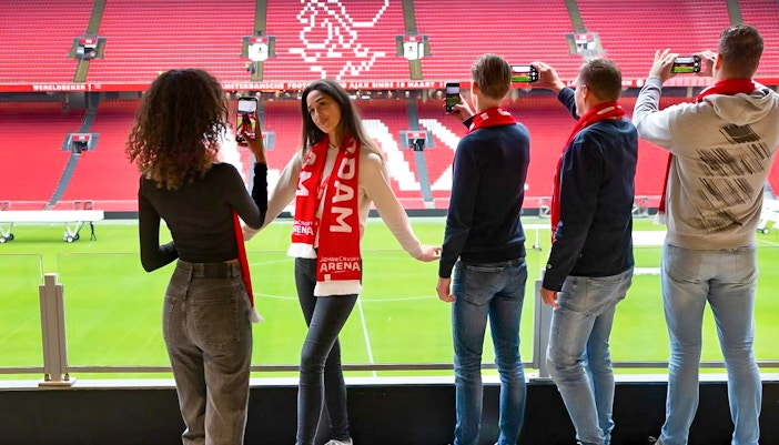 Visitors on Johan Cruijff ArenA VIP tour taking photos with scarves.