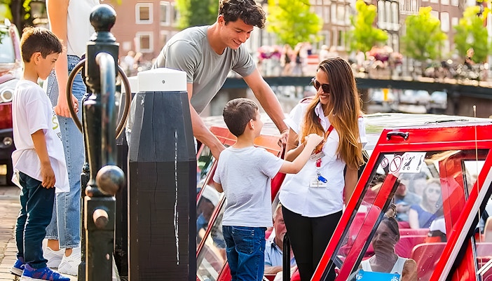 Family boarding a canal boat for City Sightseeing Amsterdam Hop-On Hop-Off tour.