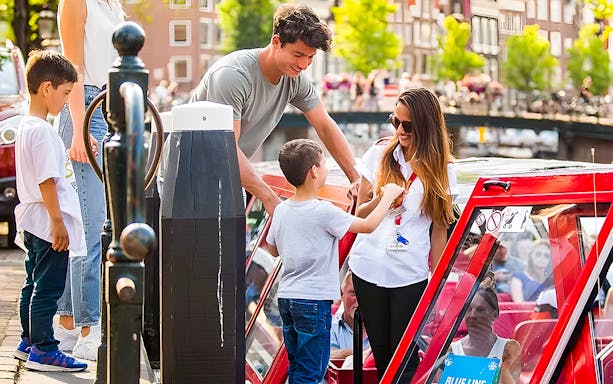 Family boarding a canal boat for City Sightseeing Amsterdam Hop-On Hop-Off tour.